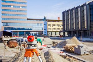 Construction survey equipment set up on an active commercial job site with buildings and site development work in progress 