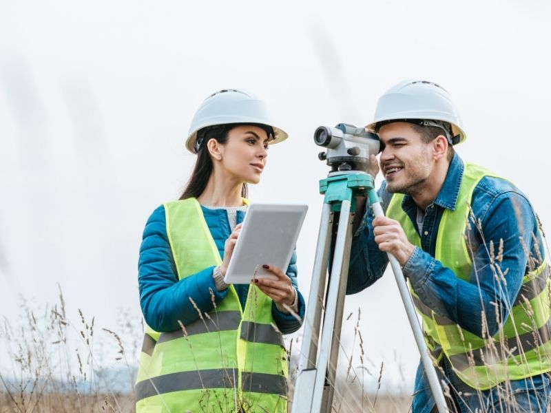 Land surveyors reviewing property information and using surveying equipment before starting a site survey.