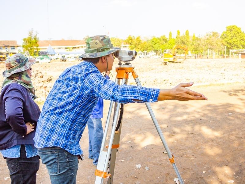 Land surveyors using surveying equipment to verify property boundaries before a real estate closing.